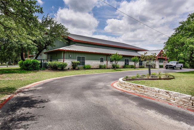 View of front of house featuring a front lawn, stone siding, metal roof, curved driveway, and board and batten siding | Image 19