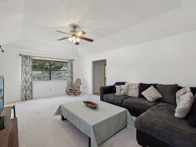 Carpeted living room featuring lofted ceiling and ceiling fan | Image 5