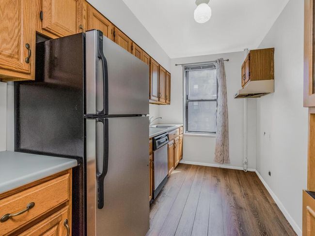 Kitchen featuring appliances with stainless steel finishes, brown cabinets, wood finished floors, and light countertops | Image 6