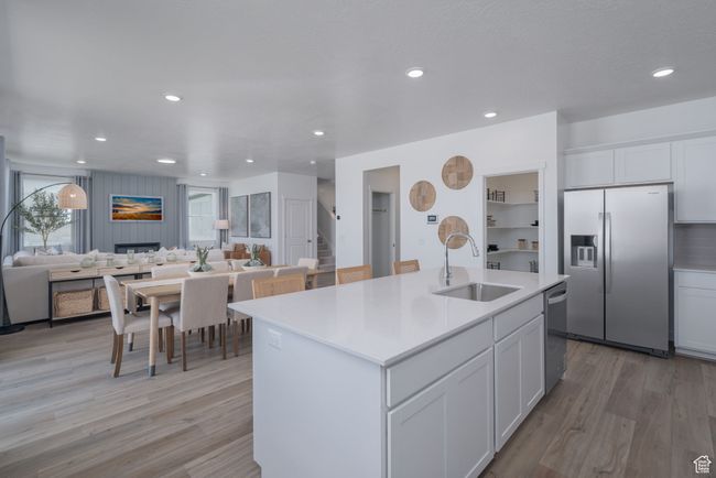 Kitchen with appliances with stainless steel finishes, a kitchen island with sink, light countertops, light wood-type flooring, and open floor plan | Image 21