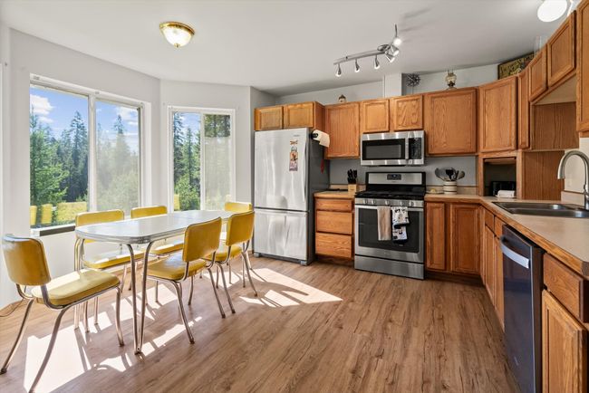 Kitchen with appliances with stainless steel finishes, a sink, light wood-type flooring, brown cabinetry, and light countertops | Image 12