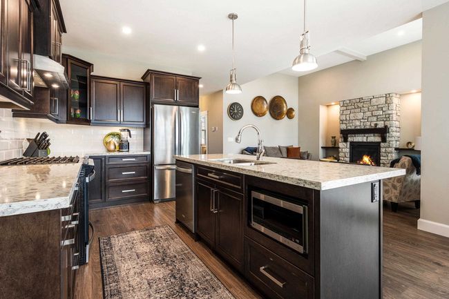 Kitchen with backsplash, a sink, stainless steel appliances, and dark wood-type flooring | Image 15