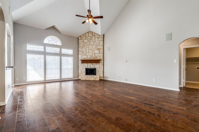 Unfurnished living room with high vaulted ceiling, dark wood finished floors, arched walkways, and a ceiling fan | Image 5