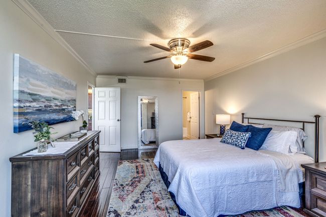 This property includes a thoughtfully curated collection of furnishings, featuring a stylish dresser, bedside tables, a colorful rug, and a queen bed set with comfortable mattresses, all of which are included with the home. | Image 13