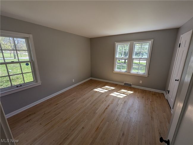 Unfurnished bedroom featuring baseboards, multiple windows, wood finished floors, and visible vents | Image 19