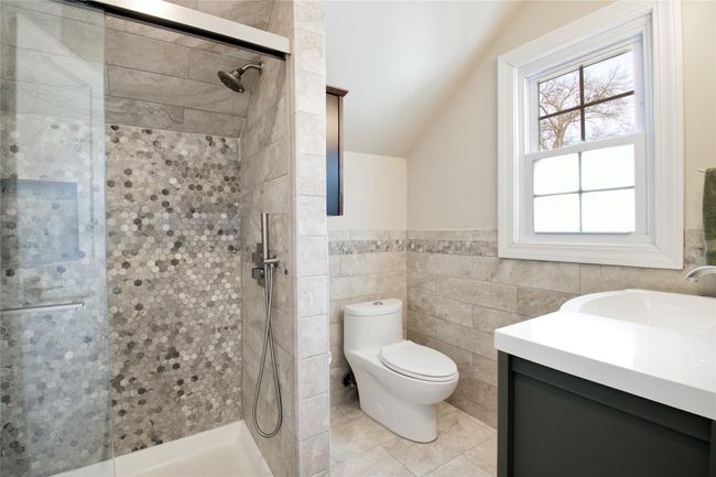 Full bath with lofted ceiling, a shower stall, toilet, vanity, and tile walls | Image 15