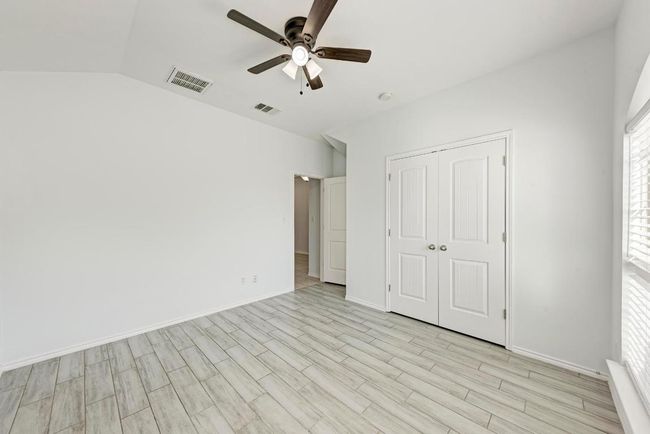 second and third bedroom featuring light wood finished floors, a closet, vaulted ceiling, baseboards, and ceiling fan | Image 27