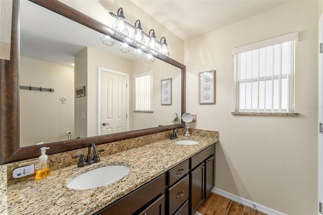 Primary bath with espresso cabinets, upgraded lighting, granite, double sinks, linen closet and window provides nice natural light | Image 17