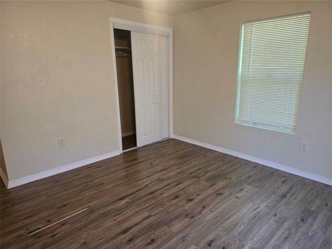 Unfurnished bedroom with dark wood-style floors and a closet | Image 12