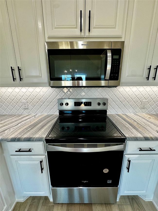 Kitchen with appliances with stainless steel finishes, backsplash, and white cabinets | Image 10