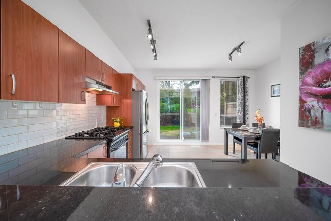 Kitchen with black range with gas stovetop, freestanding refrigerator, backsplash, under cabinet range hood, and a sink | Image 10