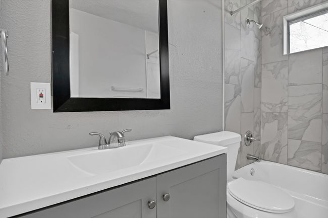 Bathroom with vanity, shower / bathing tub combination, toilet, and a textured wall | Image 13