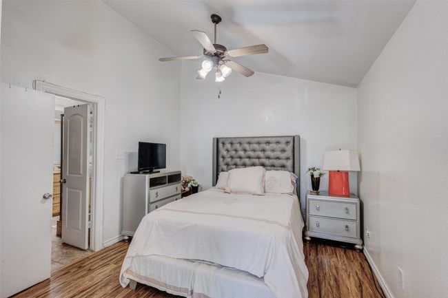 Bedroom with baseboards, lofted ceiling, wood finished floors, and ceiling fan | Image 6