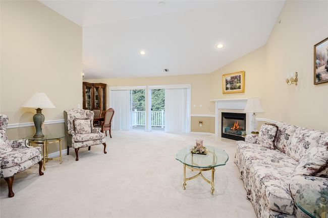 Living area with vaulted ceiling, a fireplace with flush hearth, carpet, and recessed lighting | Image 8