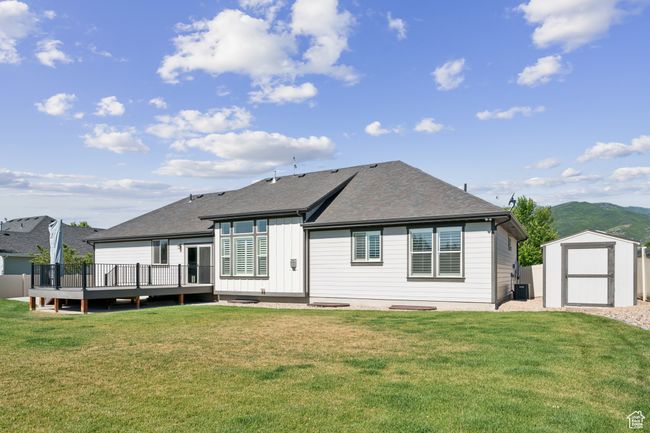 Back of house featuring a storage shed, a deck with mountain view, board and batten siding, and a yard | Image 37