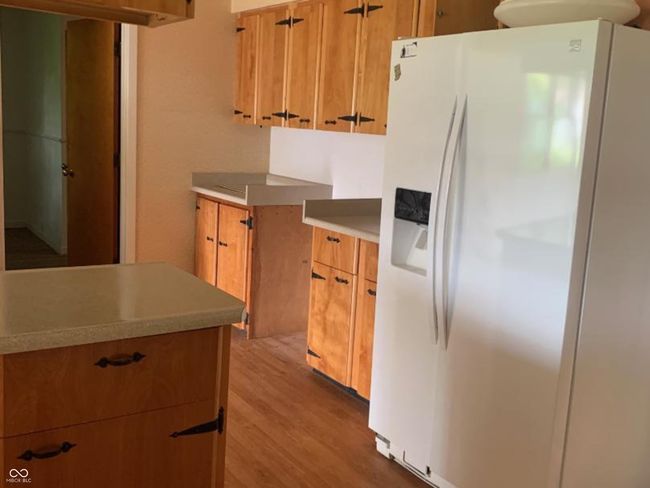 kitchen with white refrigerator with ice dispenser, dark wood-type flooring, brown cabinets, and light countertops | Image 5