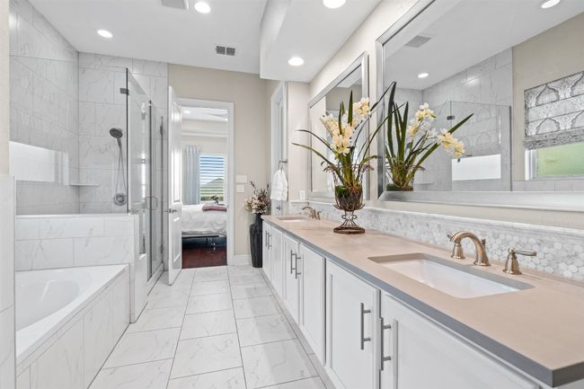 The oversized walk-in shower features elegant tile work, a frameless glass enclosure, and a built-in bench, creating a serene and rejuvenating experience. | Image 20