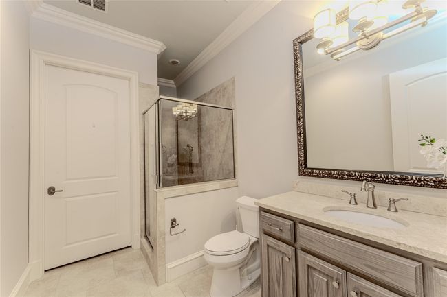 Bathroom featuring a chandelier, vanity, ornamental molding, a shower stall, and tile patterned floors | Image 31