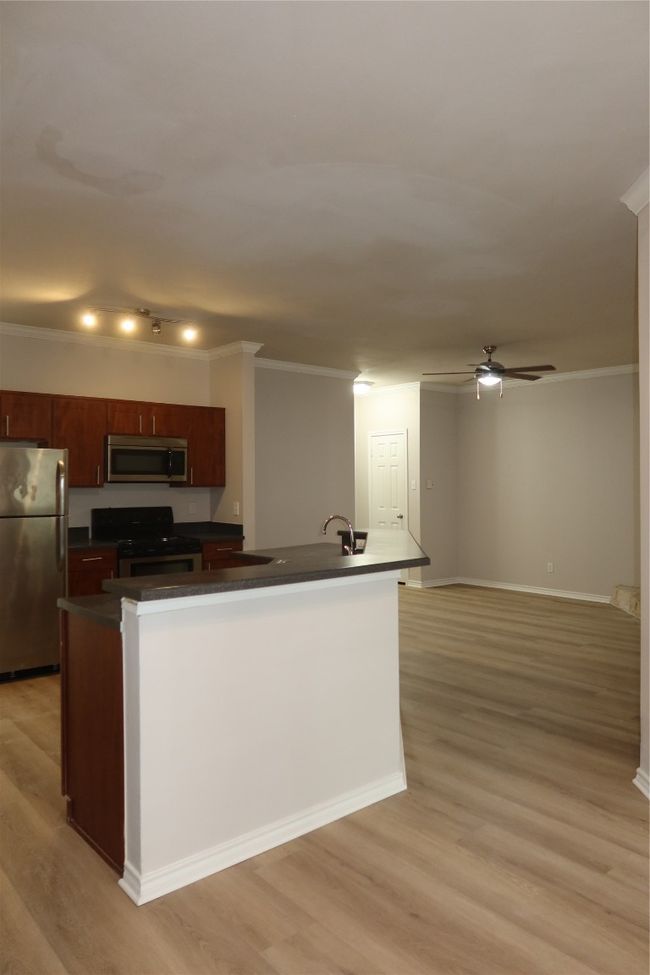 Kitchen with range, refrigerator, dark countertops, light wood-type flooring, and ornamental molding | Image 12