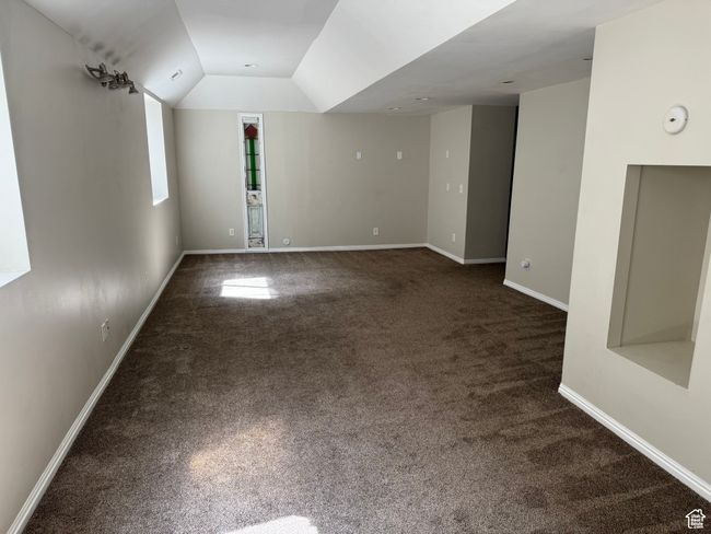Empty room with dark colored carpet, baseboards, and lofted ceiling | Image 18