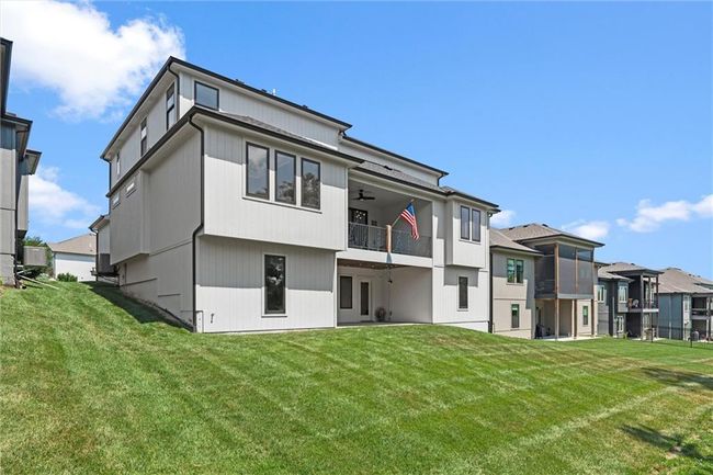 Rear view of house featuring a balcony, a yard, a ceiling fan, and a residential view | Image 38