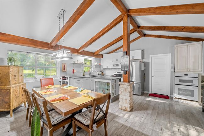 Dining area featuring vaulted ceiling with beams and light wood-type flooring | Image 13