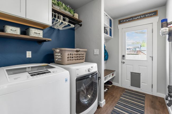 Laundry room with cabinets, shelves, washer and dryer, leading to mudroom area and backyard exit | Image 16