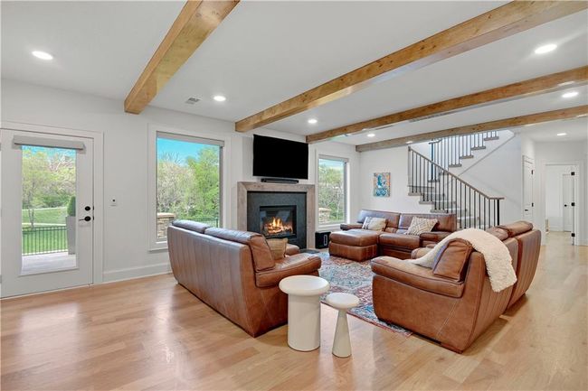 Living area with stairway, a glass covered fireplace, light wood-type flooring, beamed ceiling, and visible vents | Image 43