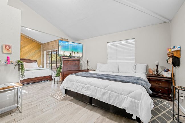 Bedroom featuring wood finished floors, wooden walls, and vaulted ceiling with beams | Image 19