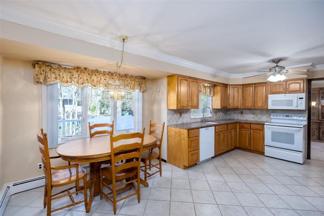 Kitchen featuring white appliances, backsplash, a sink, light tile patterned flooring, and crown molding | Image 14