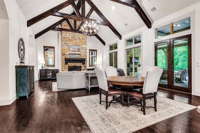 The breakfast area is just one part of this breath-taking main living area! A-frame beams are a fantastic accent to the space and draw your eye to the wall of windows highlighting the patios, pool and trees. | Image 18