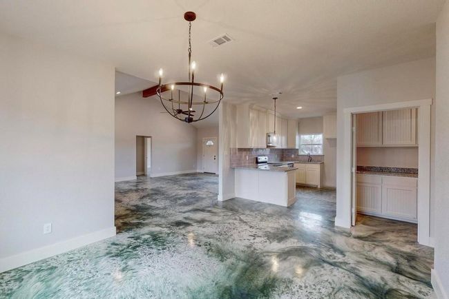 Kitchen with a notable chandelier, open floor plan, visible vents, decorative backsplash, and appliances with stainless steel finishes | Image 7