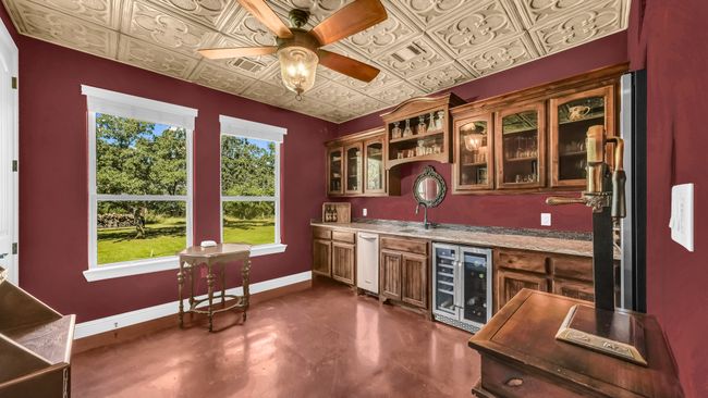 Indoor bar with wine cooler, finished concrete floors, a ceiling fan, and an ornate ceiling | Image 25
