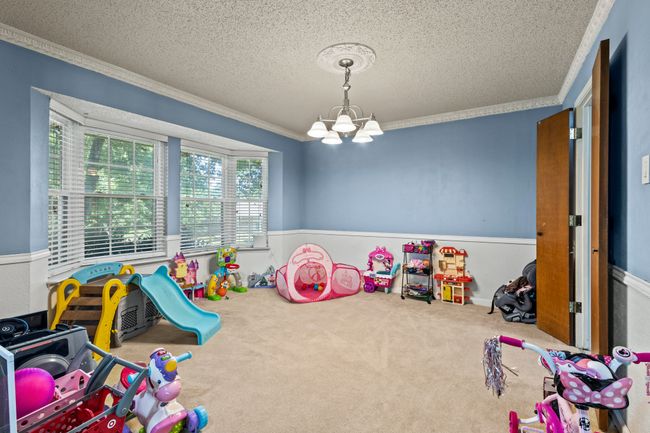 Game room featuring ornamental molding, a textured ceiling, wainscoting, a chandelier, and carpet | Image 18