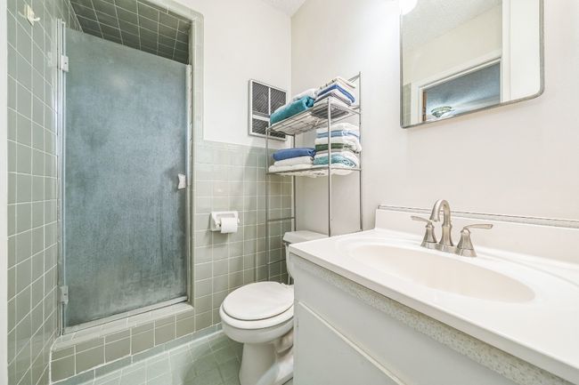 Bathroom with vanity, tile patterned floors, toilet, a shower stall, and tile walls | Image 19