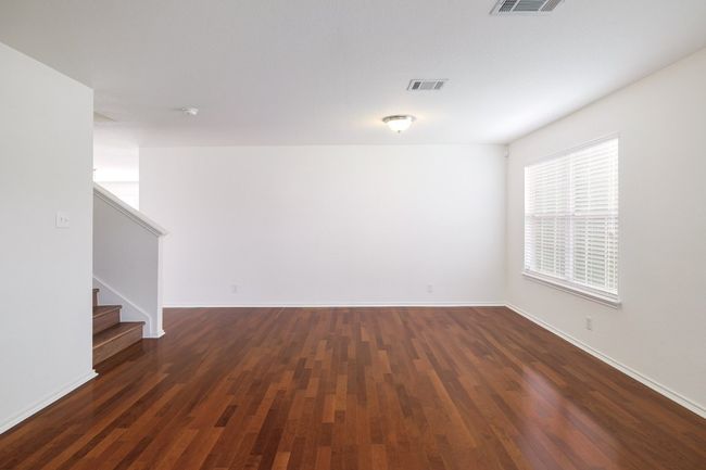 Empty room with dark wood-style floors, stairway, visible vents, and baseboards | Image 7