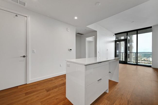 Kitchen featuring light wood finished floors, visible vents, modern cabinets, a kitchen island, and white cabinetry | Image 4