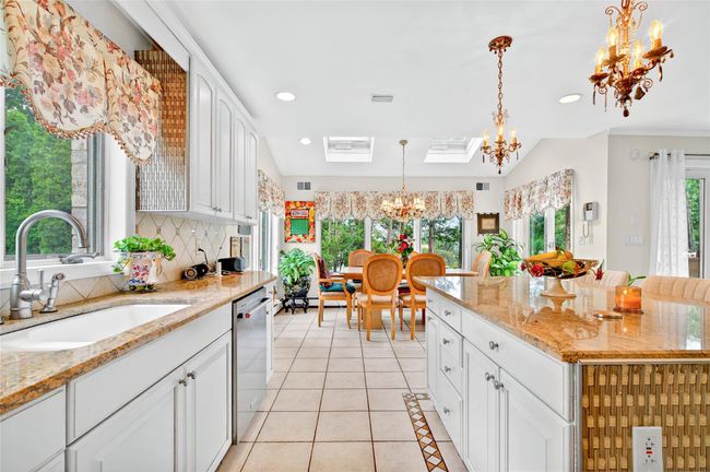 Kitchen featuring a chandelier, a sink, dishwasher, tasteful backsplash, and white cabinets | Image 21
