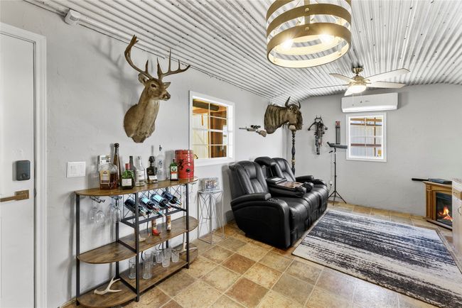 Sitting room with stone finish floor, a wall mounted air conditioner, and ceiling fan | Image 14