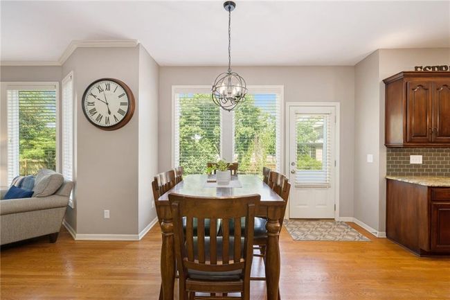 Dining area with light wood-type flooring, healthy amount of natural light, a chandelier, and baseboards | Image 12