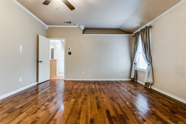 Spare room with a ceiling fan, visible vents, baseboards, hardwood / wood-style flooring, and crown molding | Image 10