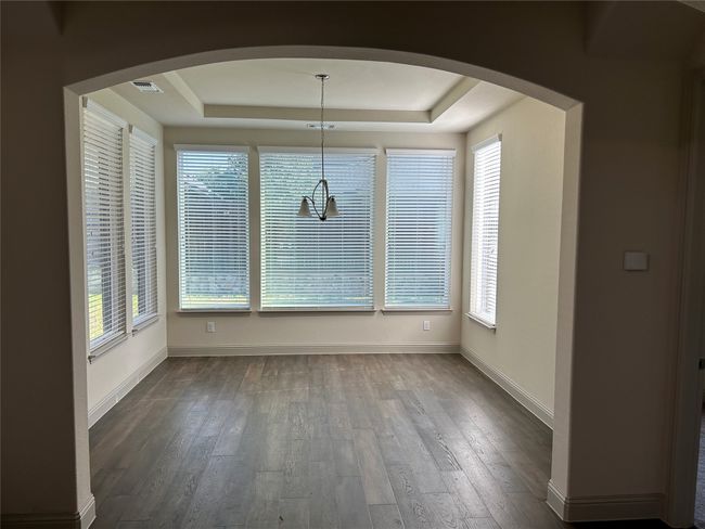 Unfurnished dining area with arched walkways, a tray ceiling, dark wood-type flooring, and baseboards | Image 15