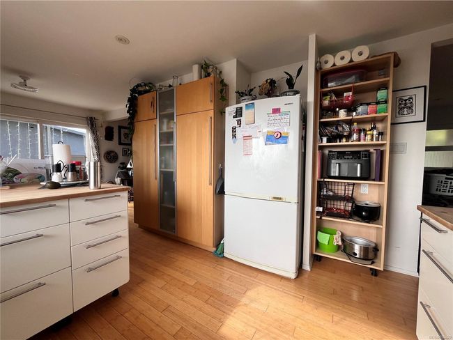 Kitchen with freestanding refrigerator, modern cabinets, butcher block counters, light wood-type flooring, and white cabinets | Image 5