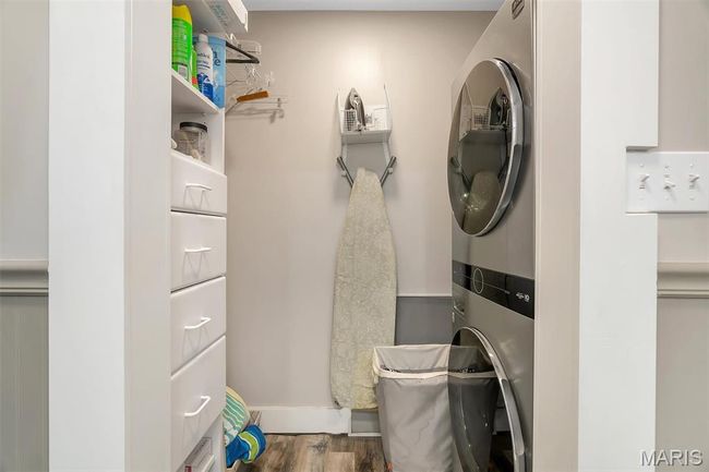 Laundry room with stacked washer / dryer and wood finished floors | Image 61