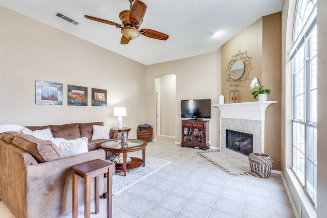 The living space is warmed by a cozy, corner fireplace with decorative mantle, ceramic tile surround and updated gas logs. | Image 9