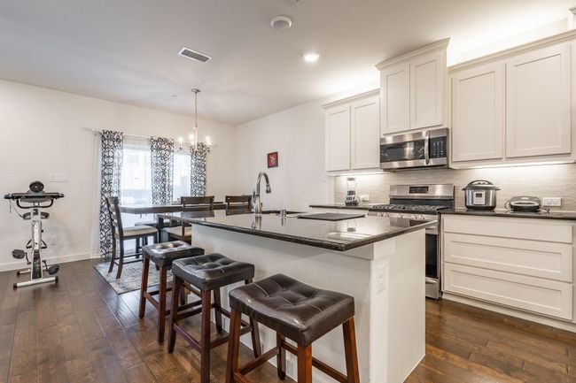Kitchen featuring a notable chandelier, dark wood-style floors, visible vents, and stainless steel appliances | Image 8