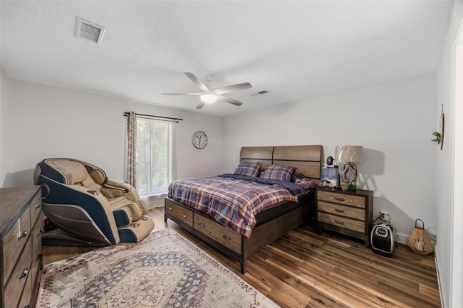 This primary bedroom features hardwood floors, a ceiling fan, and a window for natural light. | Image 9