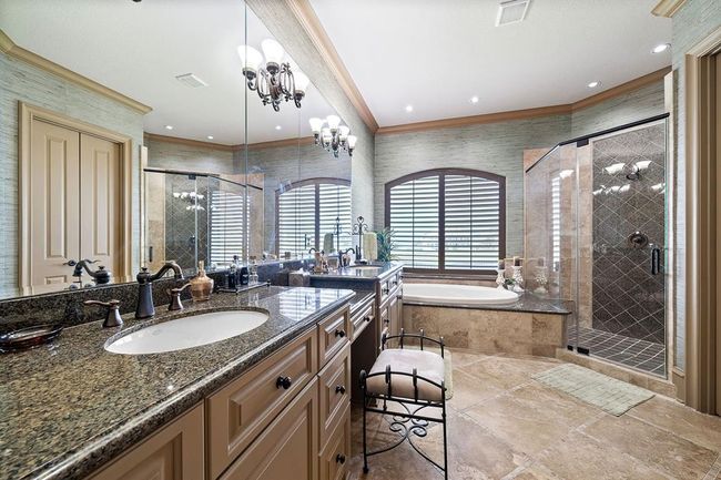 The primary bath features dual sinks, vanity area, custom finishes throughout, a luxurious walk-in shower, and a soaking tub | Image 24
