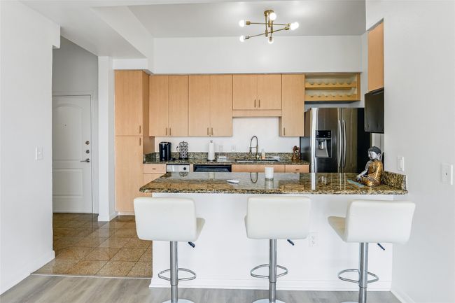 Kitchen with stainless steel fridge, a peninsula, a kitchen breakfast bar, and dark stone countertops | Image 28