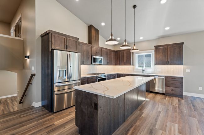Kitchen with stainless steel appliances, a sink, dark brown cabinets, backsplash, and high vaulted ceiling | Image 13